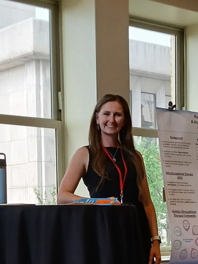 Meghan Chemidlin, OTD, beside her concussion research poster